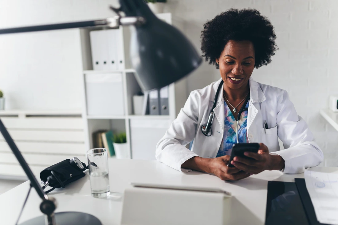 African American woman doctor working at her office online using portable inormation device Telemedicine services Primary care consultations, psychotherapy, emergency services