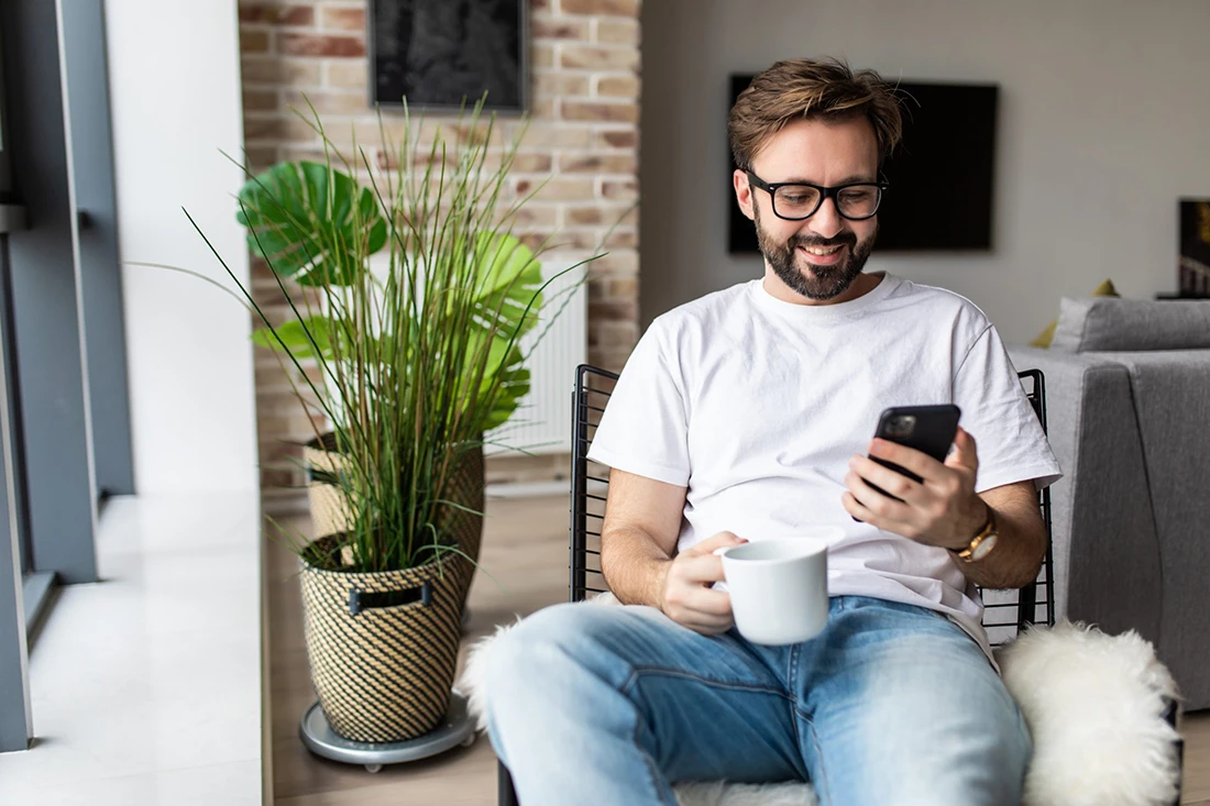 attractive young man drinking coffee and reading SMS