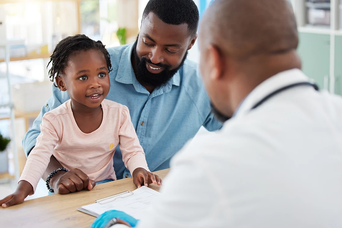 Doctor consulting with black family, baby and father in doctors office in hospital Medicine wellness, healthy child development and consultation in nurse, healthcare and medical clinic with smile