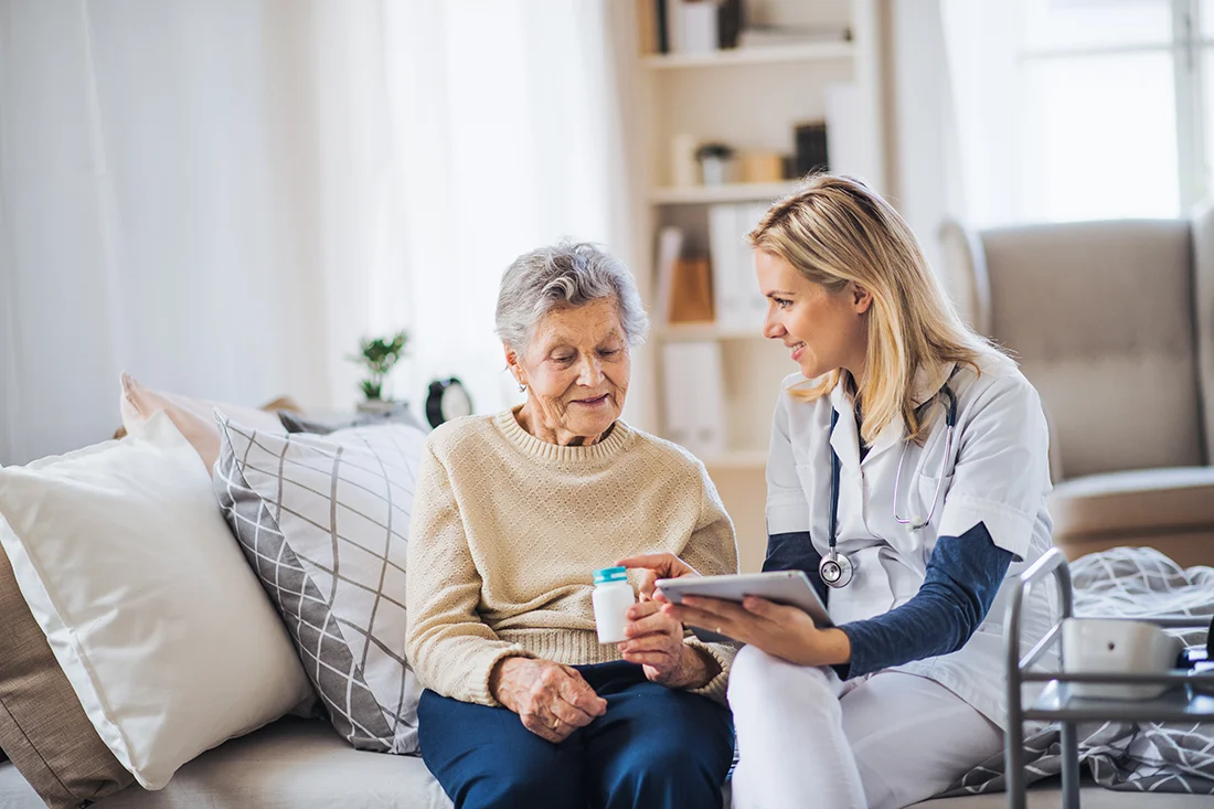 A health visitor with tablet explaining a senior woman how to take pills